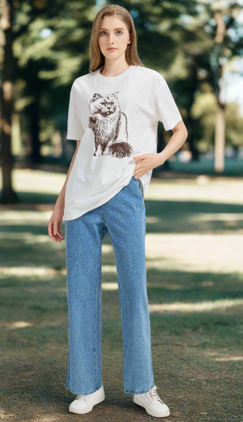 Woman wearing a white t-shirt with a graphic design and blue jeans outdoors.
