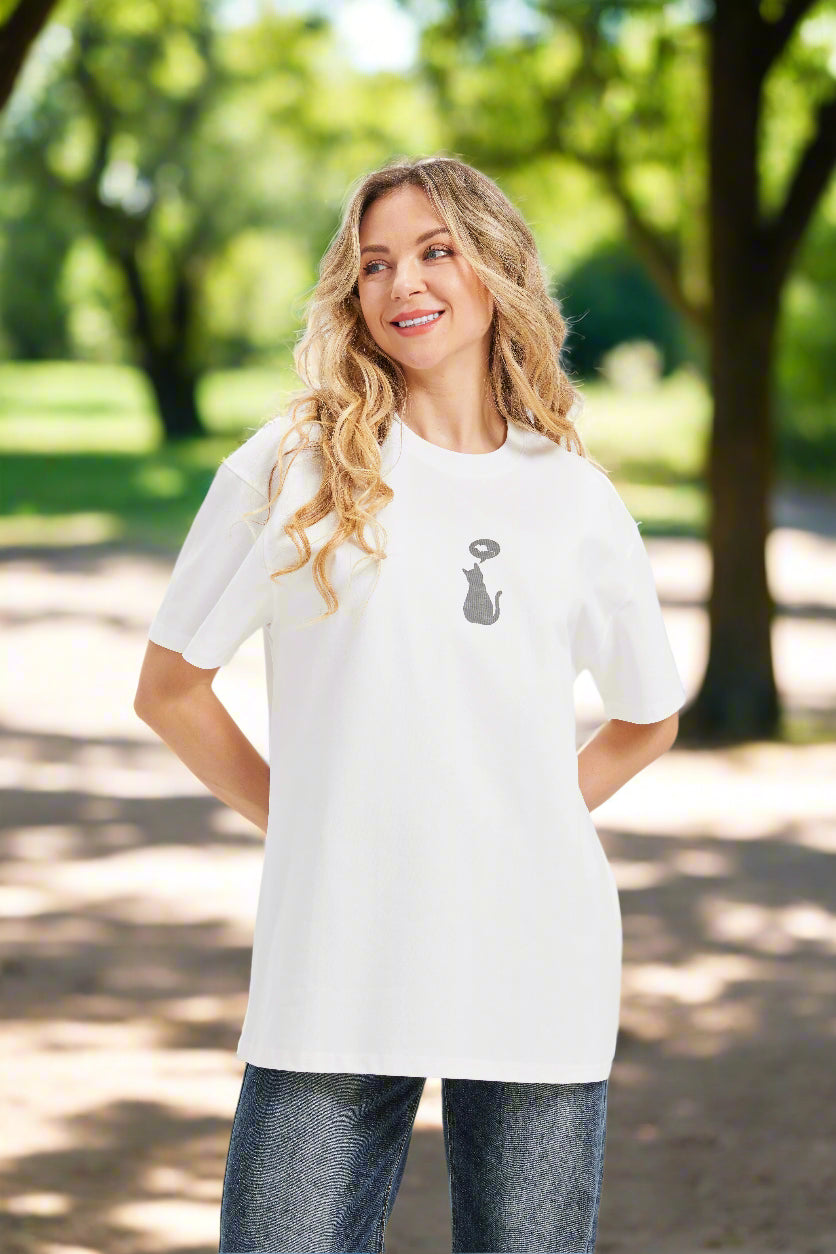 A woman in a loose fit white graphic t shirt with a cat and thought bubble image