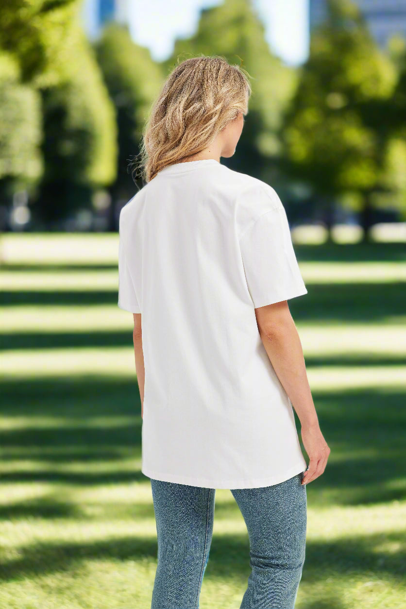 Woman wearing a white oversized t-shirt and blue jeans on a sunny park background