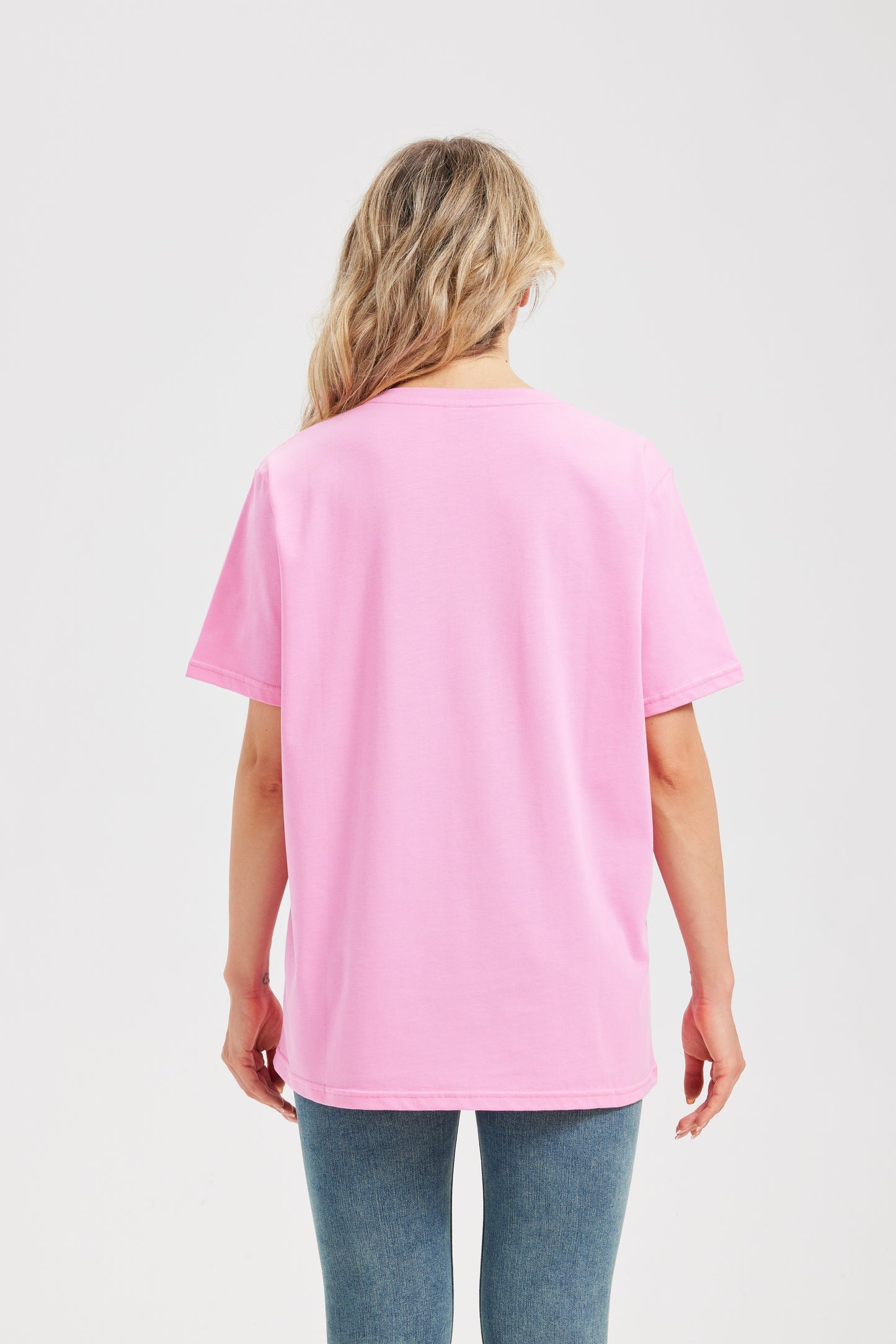 Woman wearing a pink t-shirt and blue jeans on a white background