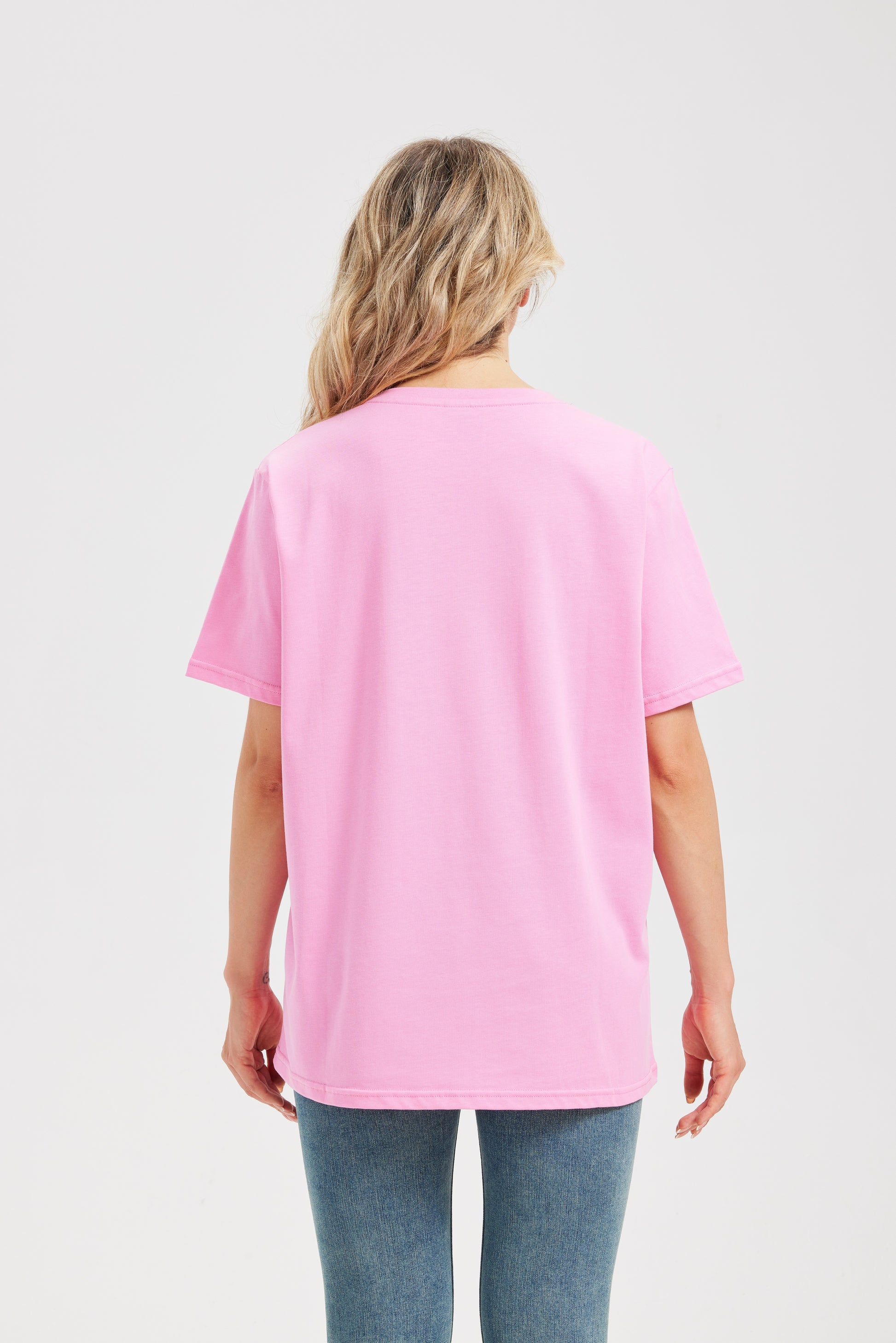 Woman wearing a pink t-shirt and blue jeans on a white background