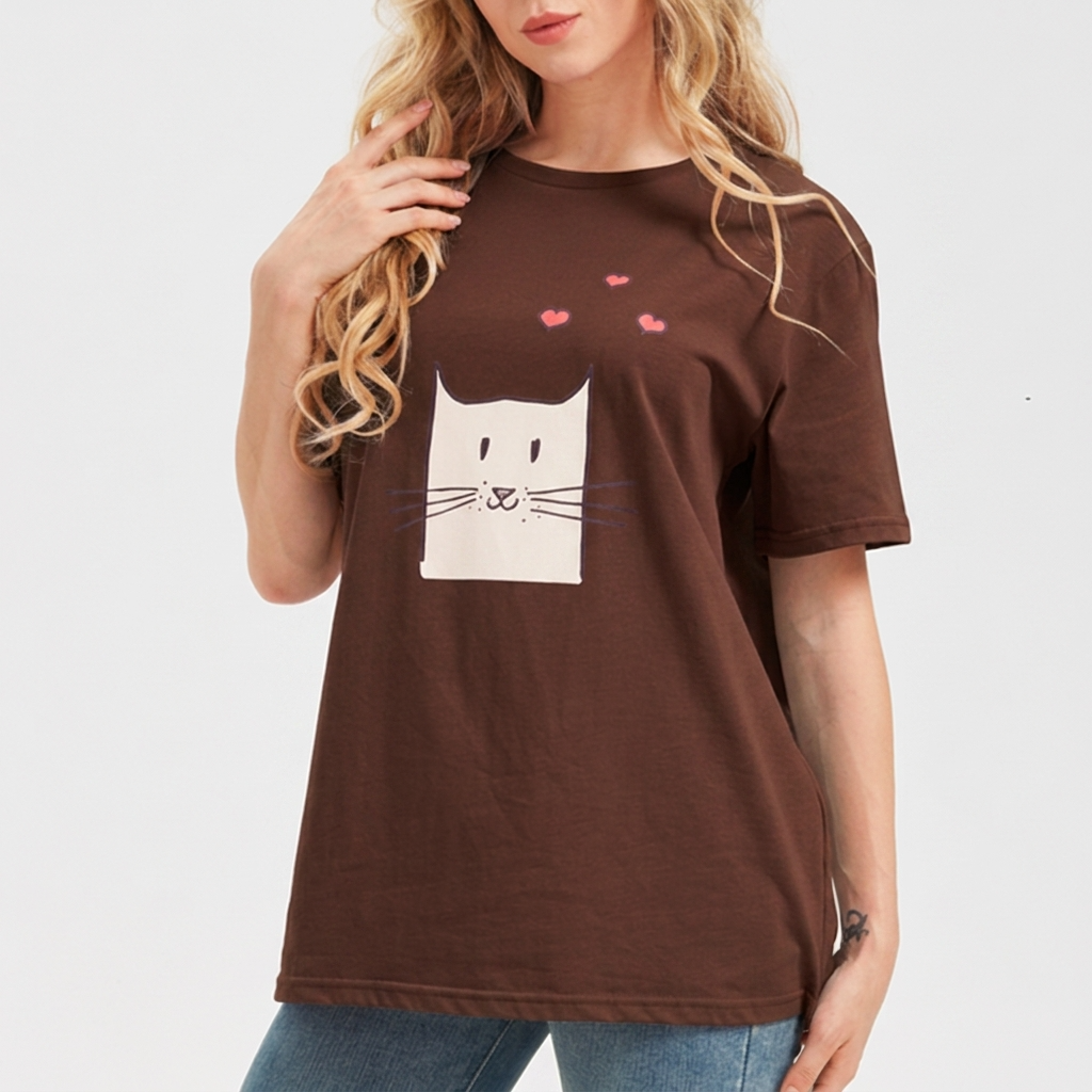 Woman wearing a brown t-shirt with a cat graphic and hearts on a white background