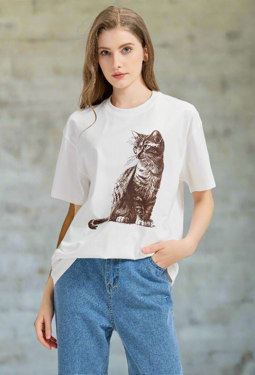 Woman wearing a white t-shirt with a cat graphic and blue jeans 