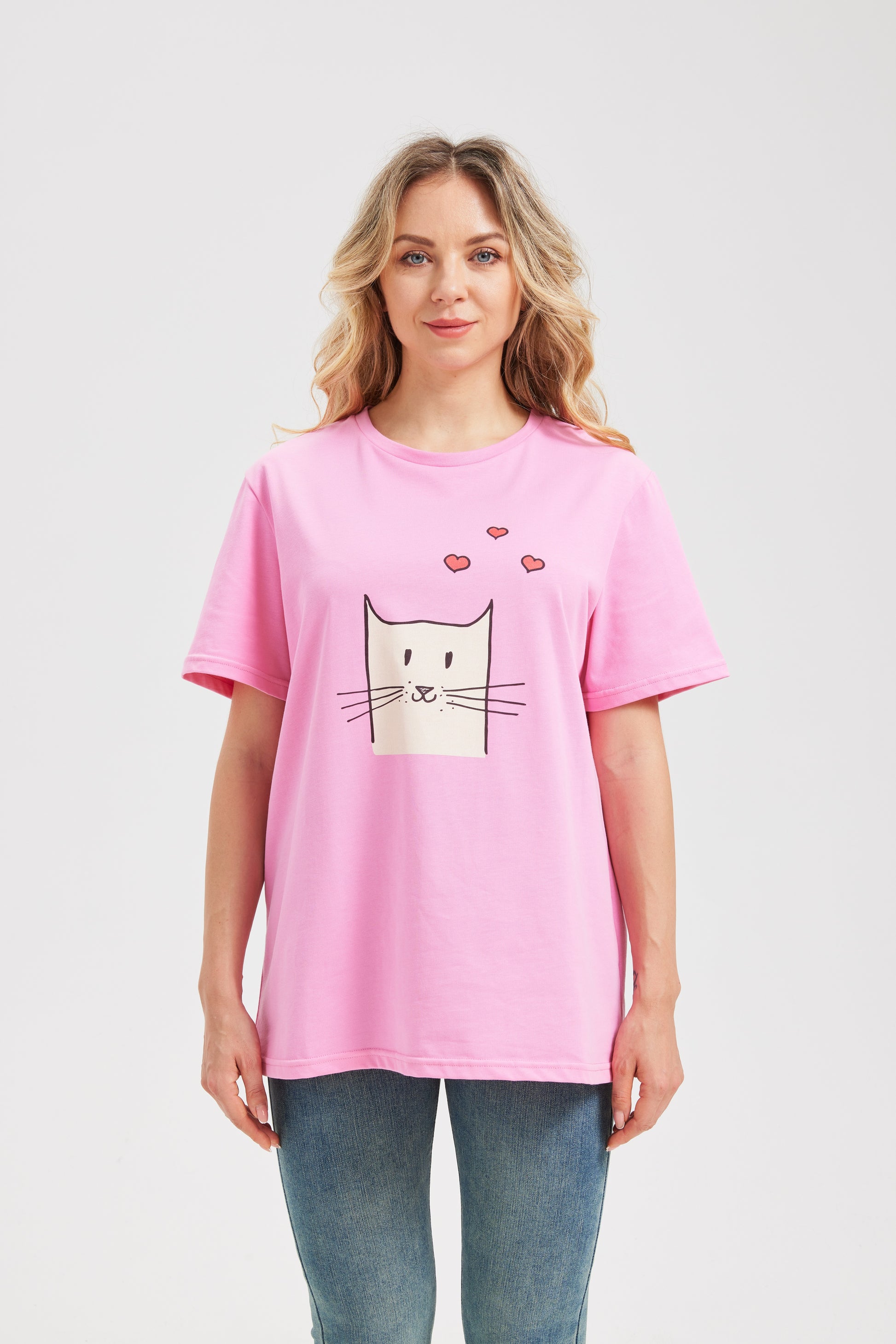 Woman wearing a pink t-shirt with a cat graphic on a plain background